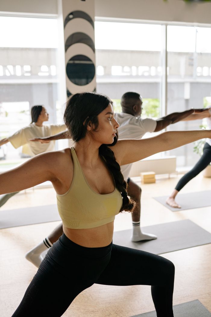 contact-img A diverse group of adults practicing yoga in a bright, modern studio, focusing on alignment and balance.